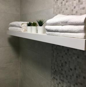 - une étagère dans une salle de bains pourvue de serviettes et de plantes dans l'établissement Appartement Miramar, à Mohammedia