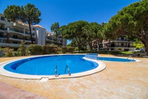 een zwembad op een binnenplaats met bomen en gebouwen bij D'Alma Falésia Beach Apartment - By Dalma Portuguesa in Albufeira