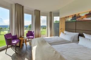 1 dormitorio con 1 cama grande y 2 sillas moradas en Hotel & Golfrestaurant Gut Wissmannshof, en Staufenberg