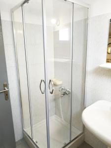 a glass shower stall in a bathroom with a sink at Sunset Apartments in Perdika