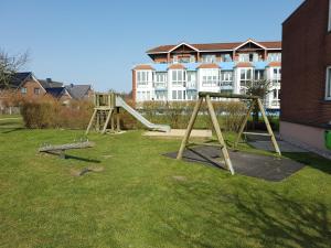 een speeltuin met twee schommels in een tuin met een gebouw bij Strand & Heide - Tolles Schwimmbad in Cuxhaven