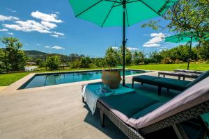 eine Terrasse mit einem Tisch und einem Sonnenschirm neben einem Pool in der Unterkunft Casa de Campo - Olive House in Areias de Vilar