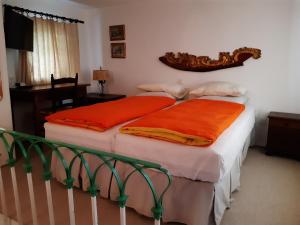 a bedroom with two beds with orange sheets at Hotel Soazza in Soazza