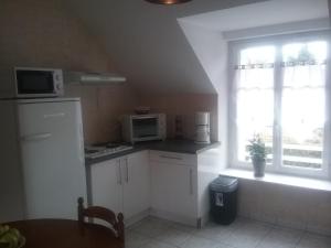 a small kitchen with white cabinets and a window at LAUBERG;APPART in Cour-Cheverny