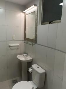 a white bathroom with a toilet and a sink at Acogedor y Elegante Estudio cerca al Prado in Cochabamba