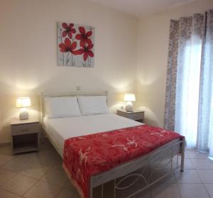 1 dormitorio con 1 cama con manta roja y 2 lámparas en STERNES house, en Agios Leon