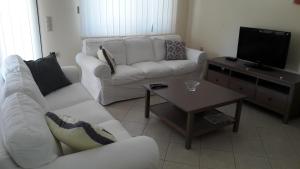 a living room with two white couches and a coffee table at STERNES house in Agios Leon