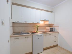 a kitchen with white cabinets and a sink and a microwave at Willa Basia in Ustronie Morskie