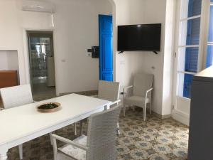 une salle à manger avec une table et des chaises blanches ainsi qu'une télévision dans l'établissement Casa direttamente sul mare 1, à Marina di Mancaversa