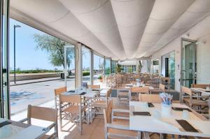 un restaurante con mesas, sillas y ventanas en Hotel Levante, en Caorle