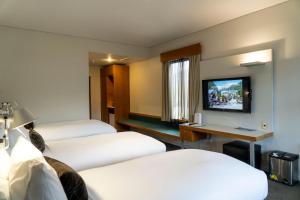 a hotel room with three beds and a television at Scenic Hotel Franz Josef Glacier in Franz Josef