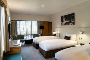 a hotel room with two beds and a television at Scenic Hotel Franz Josef Glacier in Franz Josef