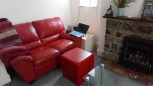 a living room with a red leather couch and a laptop at smuglers rest in Bideford