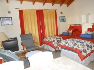 1 Schlafzimmer mit 2 Betten, einem TV und einem Stuhl in der Unterkunft Montalto in Dina Huapi