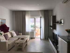 a living room with a white couch and a tv at Apartments Jani in Hvar