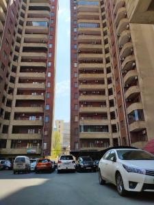 a parking lot with cars parked in front of tall buildings at Family Nizami Apartment in Baku