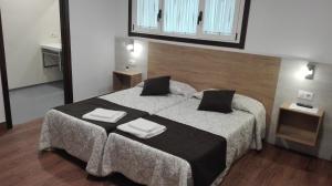 1 dormitorio con 1 cama grande y 2 toallas. en Albergue y Habitaciones Privadas Boente, en Boente