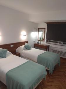 a hotel room with two beds and a flat screen tv at La mesa del cocinero in Lugo