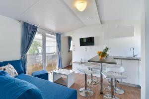 a living room with a blue couch and a kitchen at Mobile house Nord 2 Laguna in Turanj