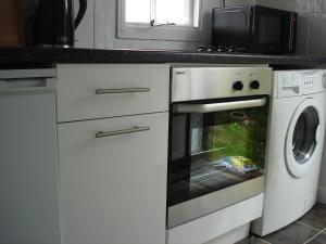 uma cozinha com um forno e uma máquina de lavar roupa em HOLLYDENE LODGE em Whitstable