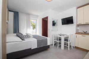 a bedroom with a bed and a table and a kitchen at Apartments and Rooms Kapulica in Tučepi