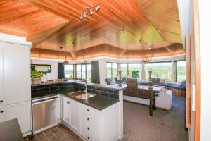 a kitchen and living room with wood ceilings and a table at Lakeview Lodge Karapiro in Cambridge