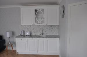 una cocina con armarios blancos y fregadero en Apartament Bello Mechelinki en Mechelinki