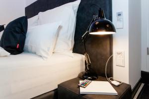 ein Schlafzimmer mit einem Bett mit einer Lampe und einem Tisch mit einem Buch in der Unterkunft Main Flat Frankfurt Offenbach in Offenbach