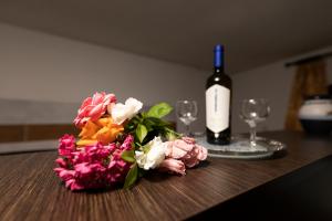 una botella de vino y flores en una mesa con copas en Arhontiko Fotini, en Kalambaka