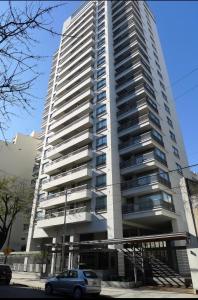 a tall building with a car parked in front of it at Topacio Tower apartamento de lujo in Buenos Aires