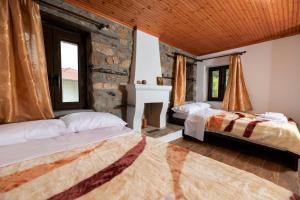 1 dormitorio con 2 camas y pared de piedra en Arhontiko Fotini, en Kalambaka