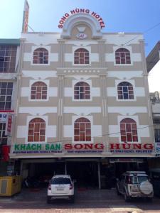 een groot gebouw met auto's geparkeerd voor het bij Song Hung Hotel in Cà Mau