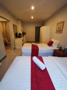 um quarto de hotel com duas camas com lençóis vermelhos e brancos em ibeyond Apartment Romklao Suvarnabhumi em Lat Krabang