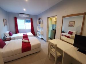 - une chambre avec 2 lits, un bureau et un miroir dans l'établissement ibeyond Apartment Romklao Suvarnabhumi, à Lat Krabang