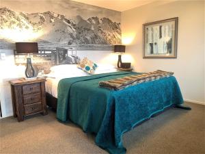 een slaapkamer met een groot bed en een blauwe deken bij 8 on Oregon Boutique Lodge in Hanmer Springs