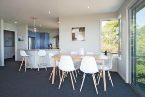 a kitchen and dining room with a wooden table and white chairs at Selah Retreat in Nelson