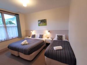 Una habitación de hotel con dos camas y una ventana. en Elm Lodge Bright, en Bright 41 fotos más