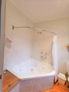 a white bathroom with a bath tub in a room at Elm Lodge Bright in Bright