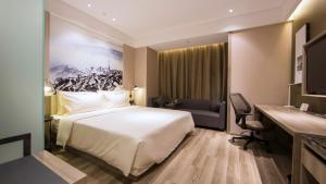 HoumaにあるAtour Hotel (Houma Xintian Square)のベッドとデスクが備わるホテルルームです。