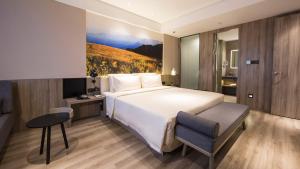 HoumaにあるAtour Hotel (Houma Xintian Square)の大型ベッドとテレビが備わるホテルルームです。