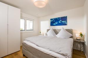ein weißes Schlafzimmer mit einem großen Bett und einem Fenster in der Unterkunft Alma in Olpenitz