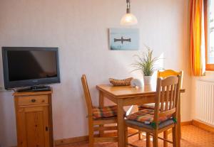 a dining room table with a television and a table and chairs at Strandhaus Nr. 9 OG re. in Dahme