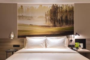 een slaapkamer met een bed met een schilderij aan de muur bij Atour Hotel (Kong Family Mansion) in Qufu