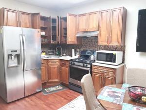 a kitchen with wooden cabinets and a stainless steel refrigerator at Rochester's Place in Brooklyn