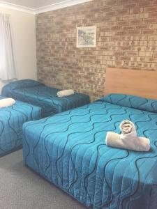 Habitación de hotel con 2 camas con sábanas azules en Nanango Fitzroy Motel, en Nanango
