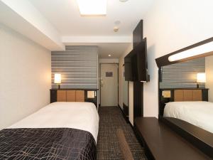 a hotel room with two beds and a flat screen tv at APA Hotel Kyoto Ekimae Chuoguchi in Kyoto