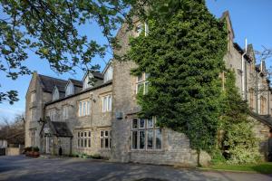 um antigo edifício de pedra com uma grande árvore em Stonecross Manor Hotel em Kendal