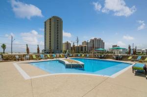 a large swimming pool with a tall building in the background at Comfort Inn & Suites Gulf Shores East Beach near Gulf State Park in Gulf Shores