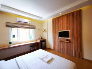 a hotel room with a bed and a television at Triple Trees Hotel in Pathum Thani +32 photos
