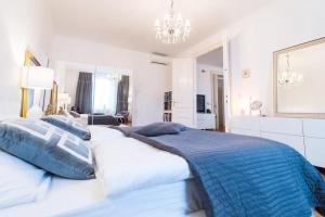 a large white bed with blue and white pillows at Relax Centar Apartment in Podgorica